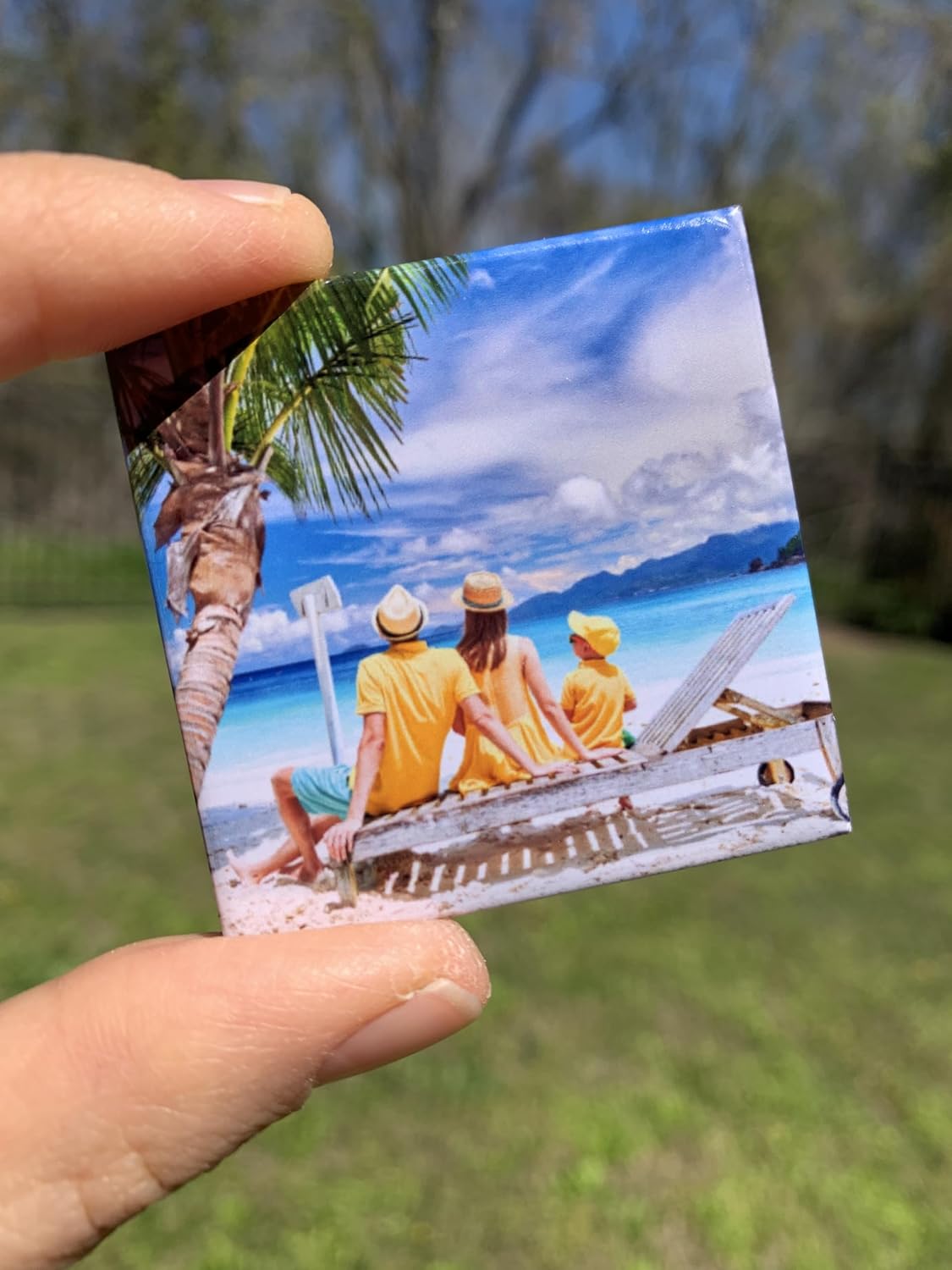 Small photo of people on a beach held by a hand with a blurred natural background