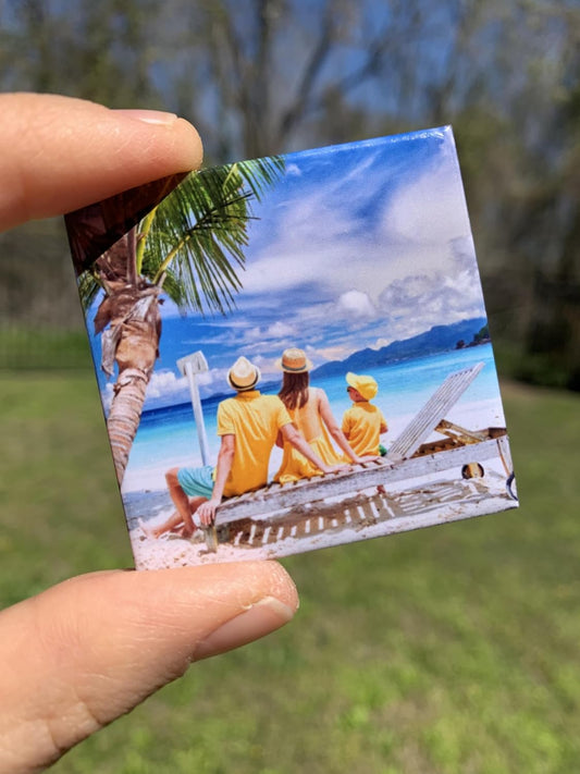 Small photo of people on a beach held by a hand with a blurred natural background